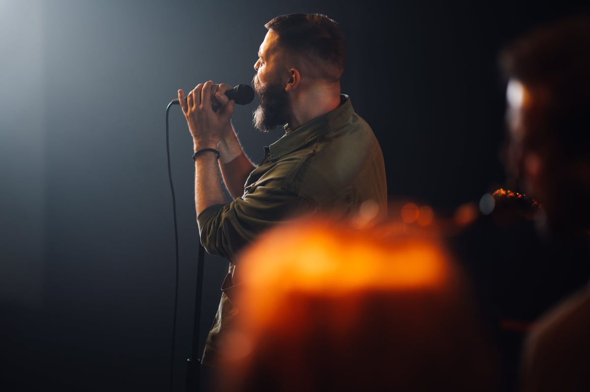 Male singer singing passionately during a concert, captivating the audience with his powerful voice
