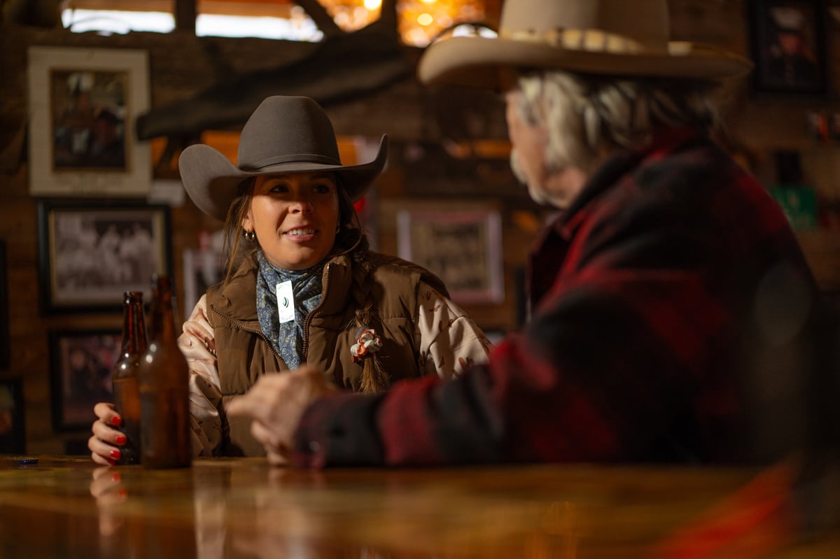 Couple wearing cowboy hats drinking at rustic saloon bar