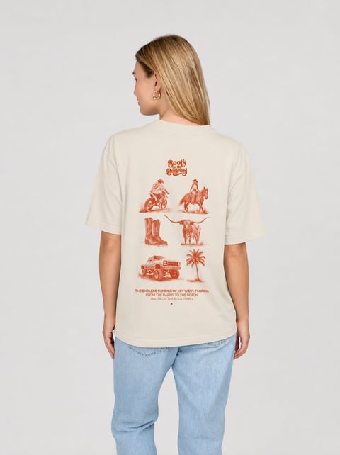 Woman wearing cream-colored t-shirt with red Western-themed graphics and text on back, paired with light blue jeans, standing against white background