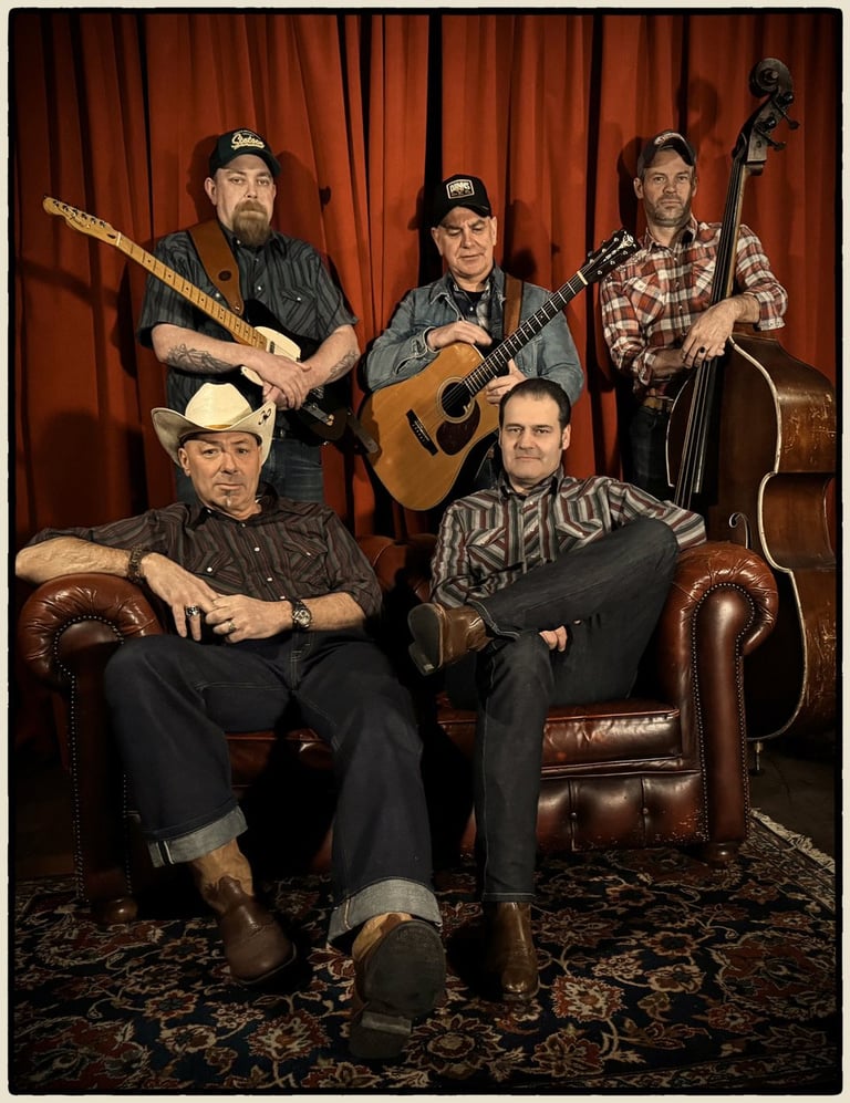 Five musicians posing with instruments against red curtains, sitting and standing around leather furniture