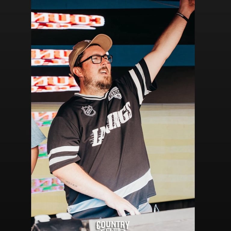 Man in sports jersey and cap raises his arm while speaking at a radio station event