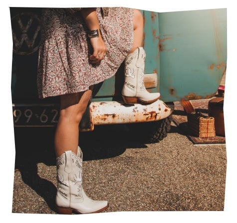Two people wearing white cowboy boots standing on gravel