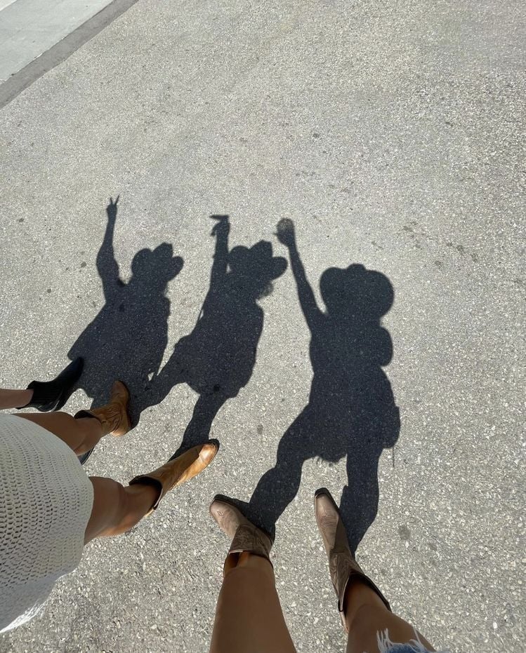Three peoples shadows on concrete ground, viewed from above with their feet visible